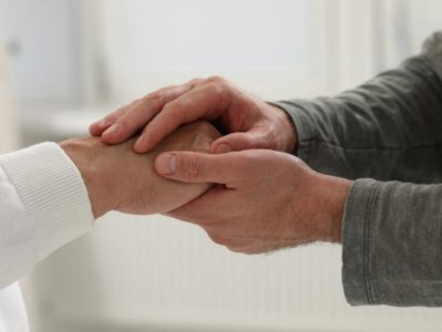 Dos persones agarrándose les manes nuna imaxe sobre atención social y cuidaos.