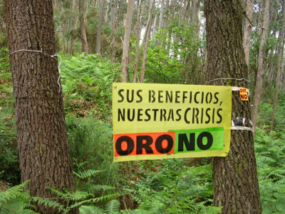 Cartelu col mensaxe «Oro No» colocáu ente árboles nun monte de Salave.