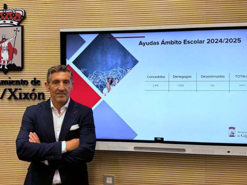 Conceyal d’Educación del Conceyu de Xixón delantre d’una pantalla con información sobre ayudes escolares.