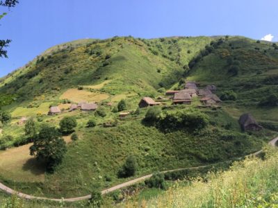 Braña La Pornacal, en Somiedu, con construcciones tradicionales de techu vexetal nuna ladera verde