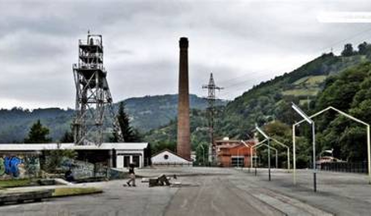 Instalaciones mineroindustriales con castillete y chimenea nun paisaxe asturianu