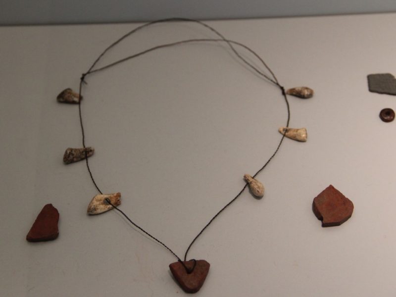 Collar y fragmentos d’ocre de La Lluera amosaos nel Muséu Arqueolóxicu d’Asturies.