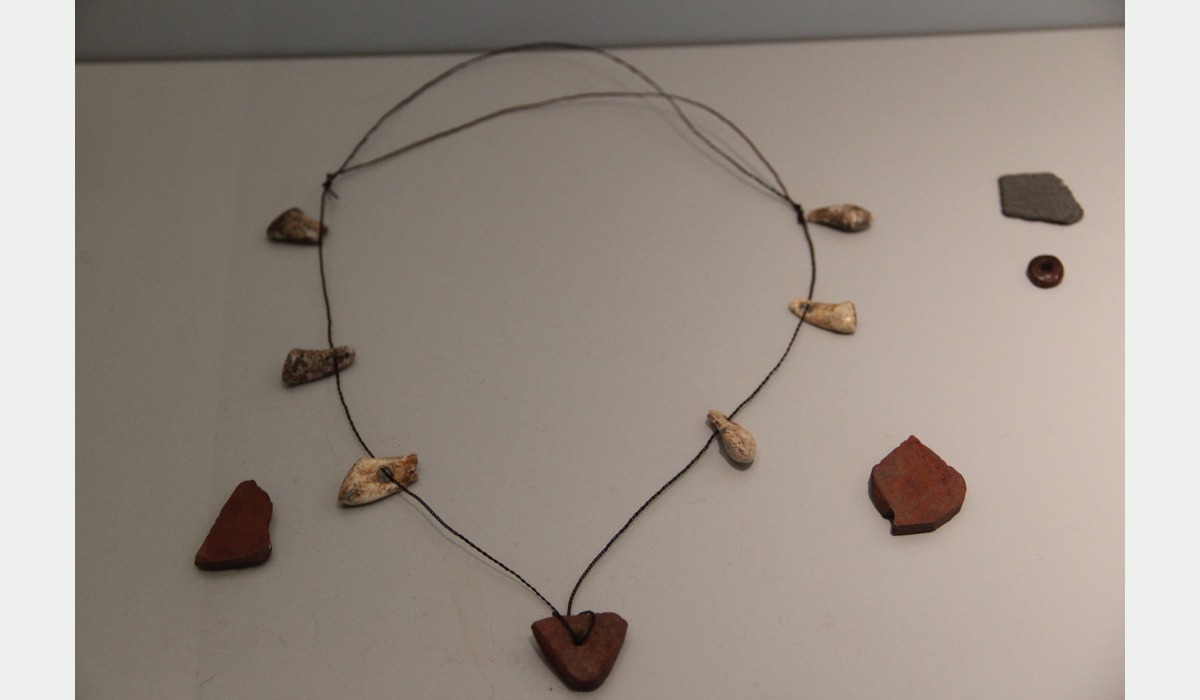 Collar y fragmentos d’ocre de La Lluera amosaos nel Muséu Arqueolóxicu d’Asturies.