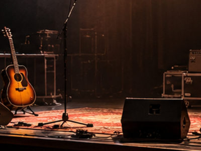 Escenariu vacíu con guitarra, micrófonos y lluz teatral, nuna illustración xenerada con IA