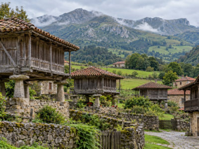 Illustración d’una aldea asturiana ente montes y praderíes