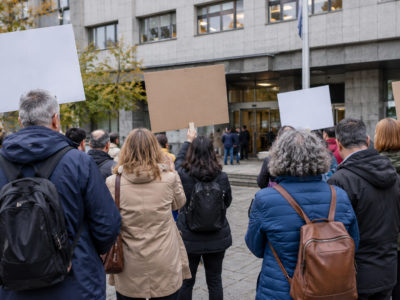Un grupu de persones con pancartes ensin testu concentráu énte la entrada d’un edificiu públicu